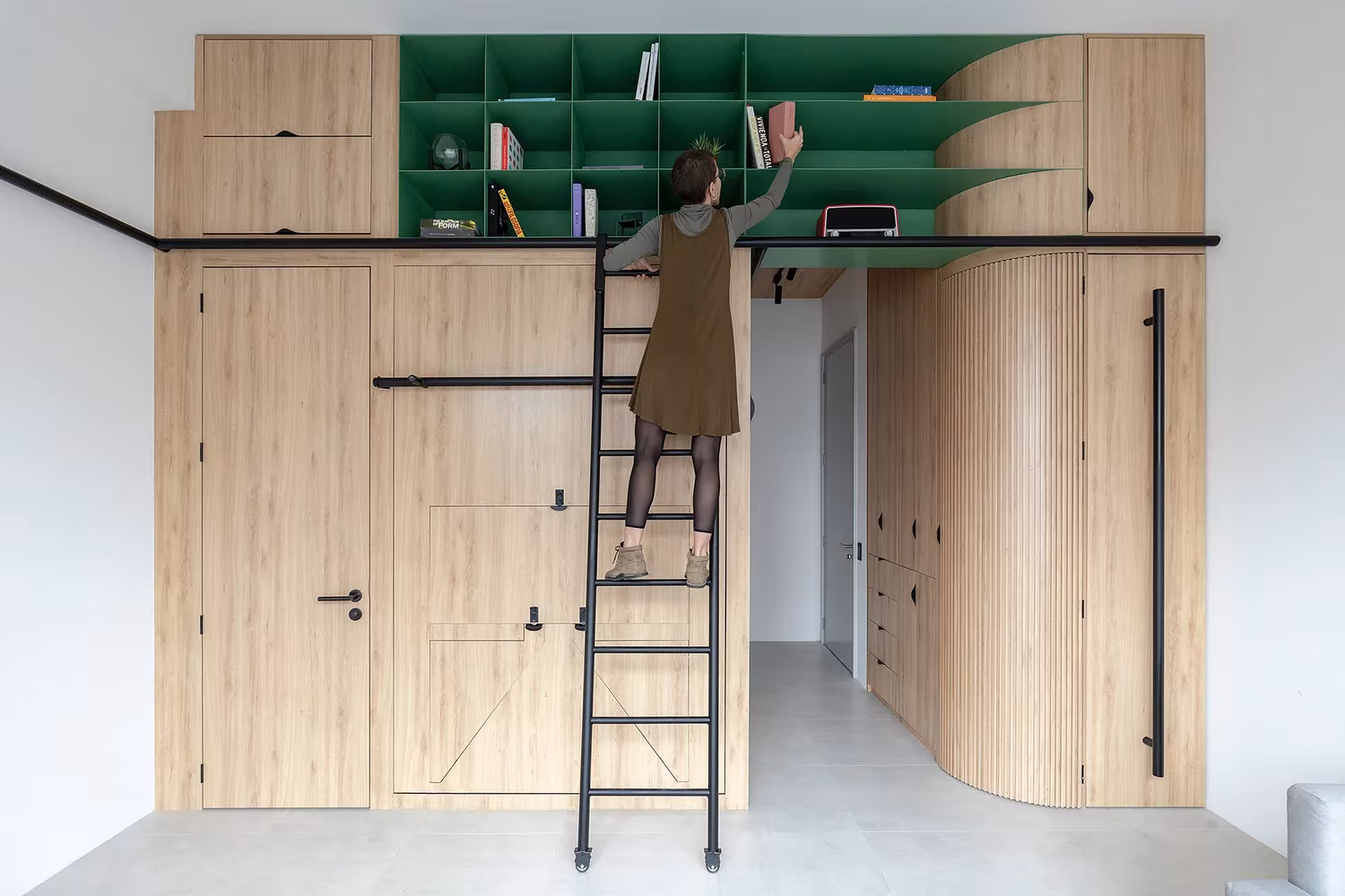 Persona sobre la escalera alcanzando las estanterías altas del módulo de madera en Doméstico, Quito