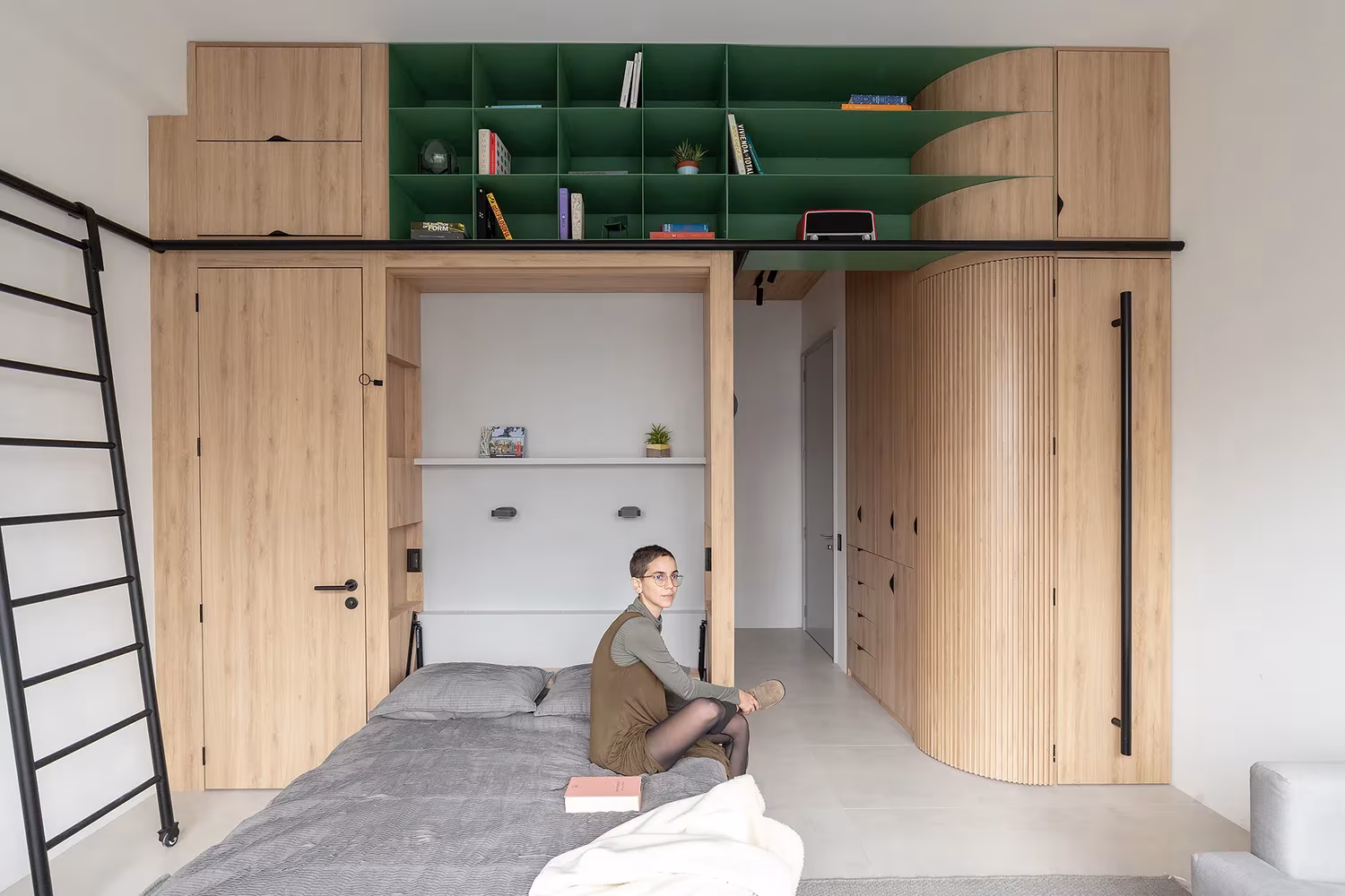 Cama abierta en el hueco central del mueble multifunción de roble y estantería verde en Doméstico