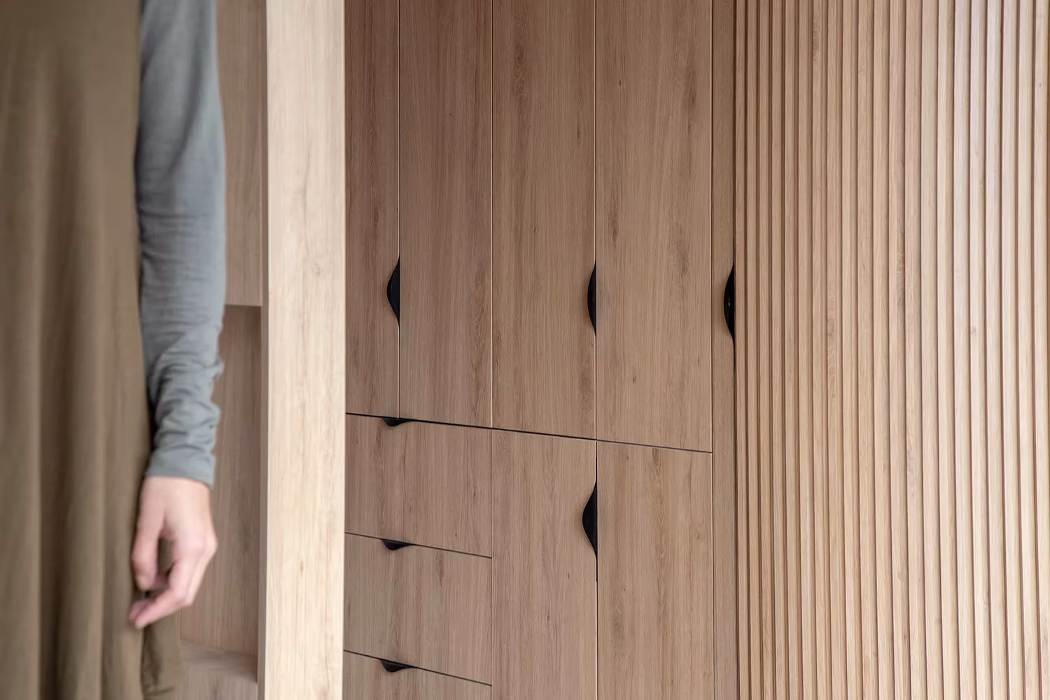 Detalle de las puertas de madera lamelada y los cajones de tirador triangular del módulo Doméstico