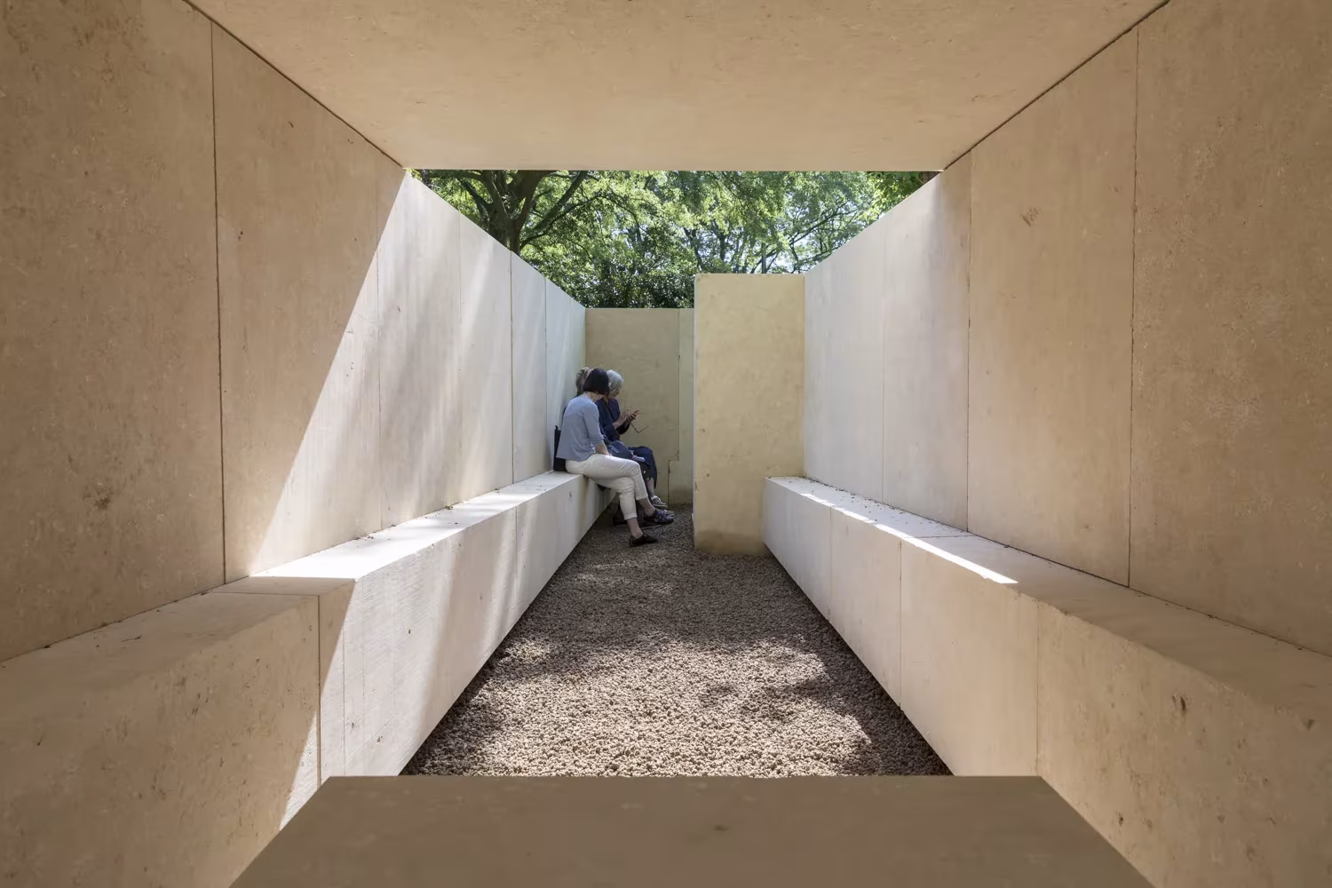 Interior a cielo abierto de la capilla de Souto de Moura, con bancos de piedra a ambos lados y una persona al fondo