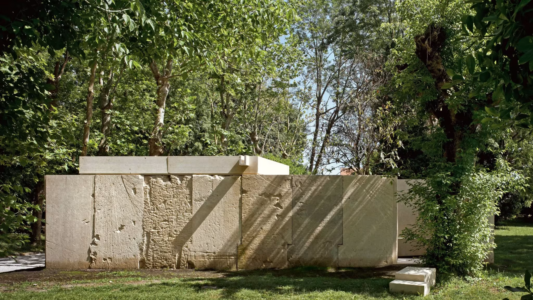 Capilla de bloques de piedra de Vicenza entre árboles, obra de Eduardo Souto de Moura en Venecia
