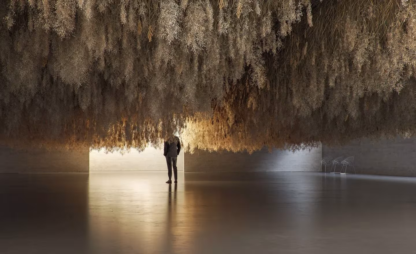 Visitante bajo el techo de hierba seca suspendida de la instalación French Exit de Tadao Cern