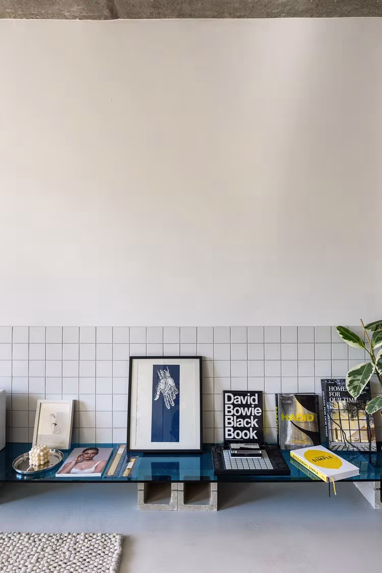 Banco de azulejo blanco con libros y objetos bajo un muro encalado en la Casa I O de Alan Prekop