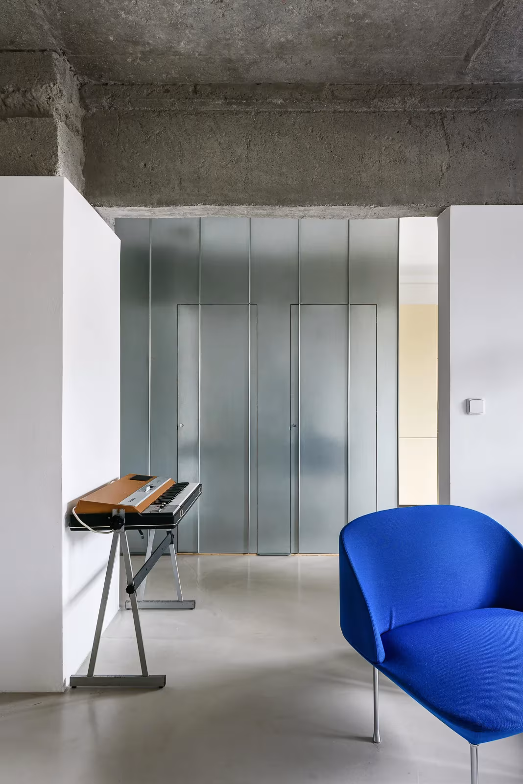 Loft de la Casa I O con forjado de hormigón visto, armarios de vidrio translúcido y butaca azul