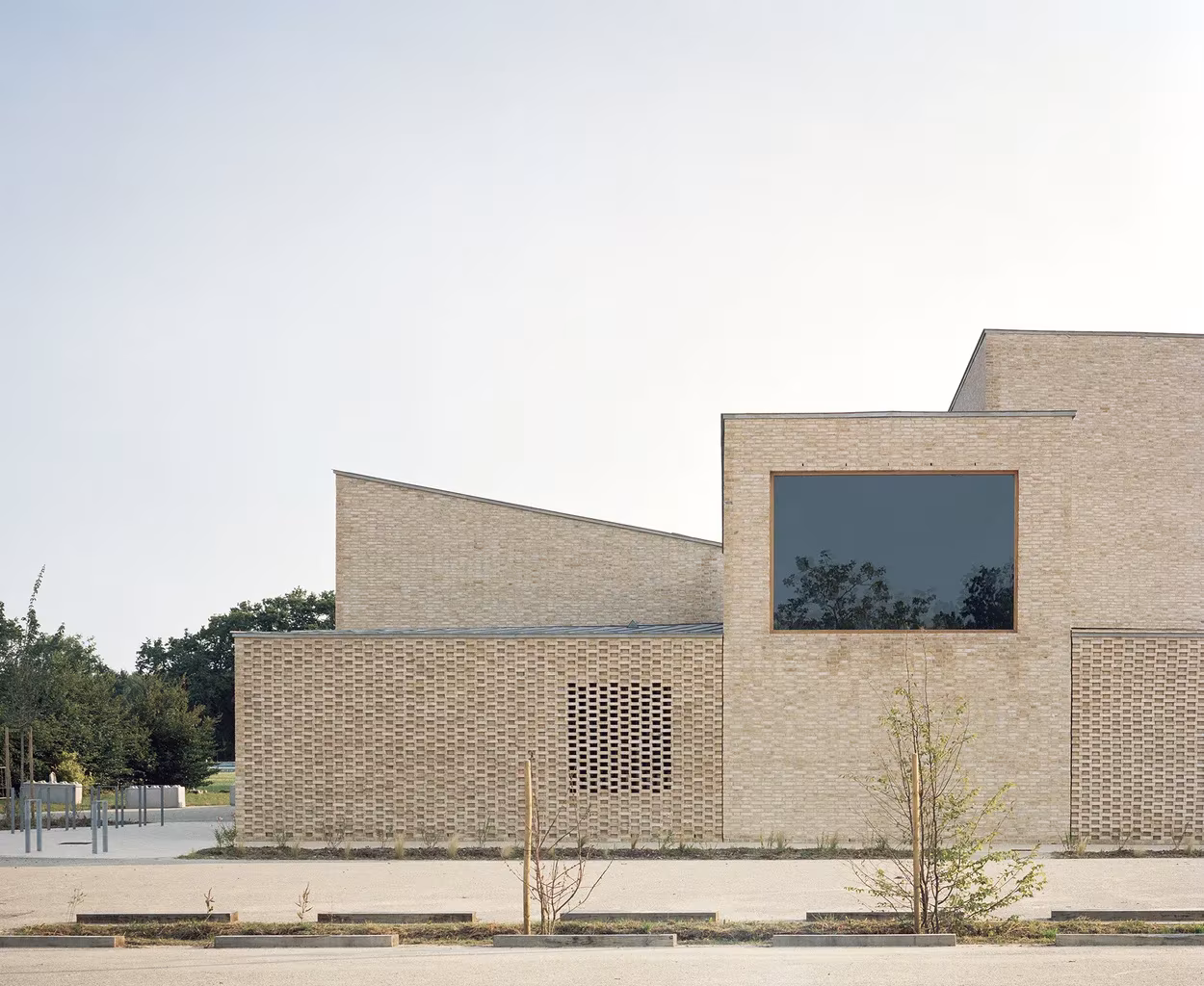 Fachada de ladrillo con celosía y ventana cuadrada del polideportivo de RAUM en Saint-Jean-de-Boiseau
