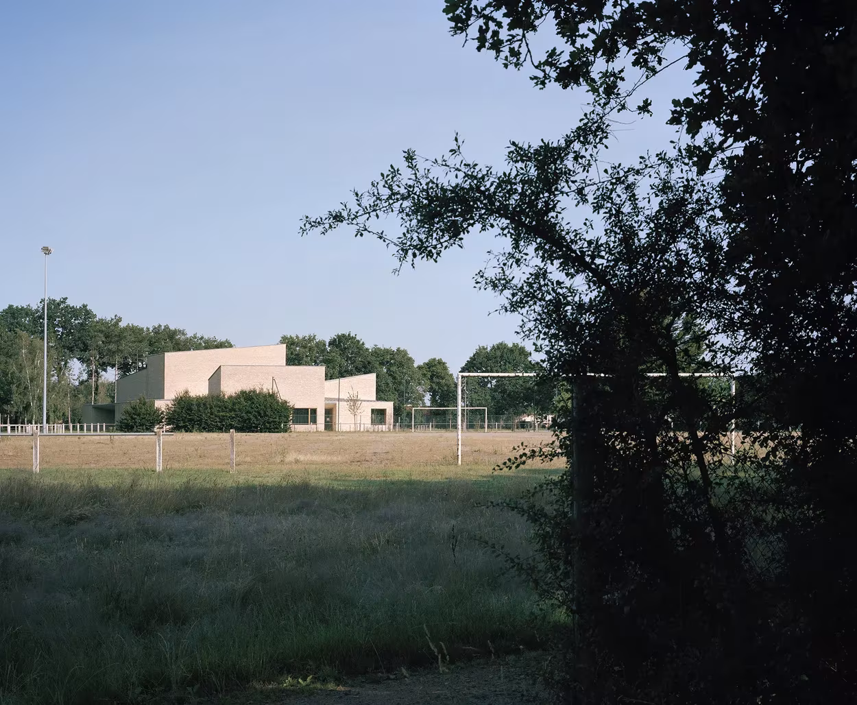 Volúmenes de ladrillo claro del polideportivo de RAUM entre la hierba y los árboles de Saint-Jean-de-Boiseau