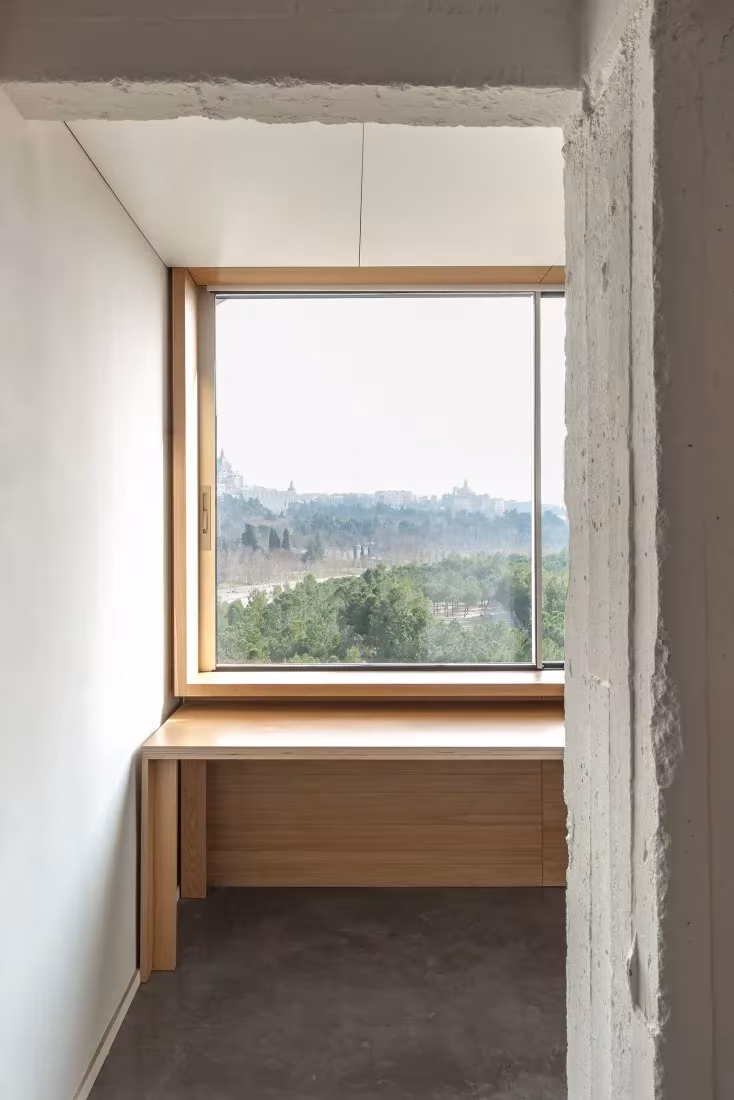 Ventana con marco de madera y escritorio empotrado que mira a la ciudad en la reforma de Pachón-Paredes