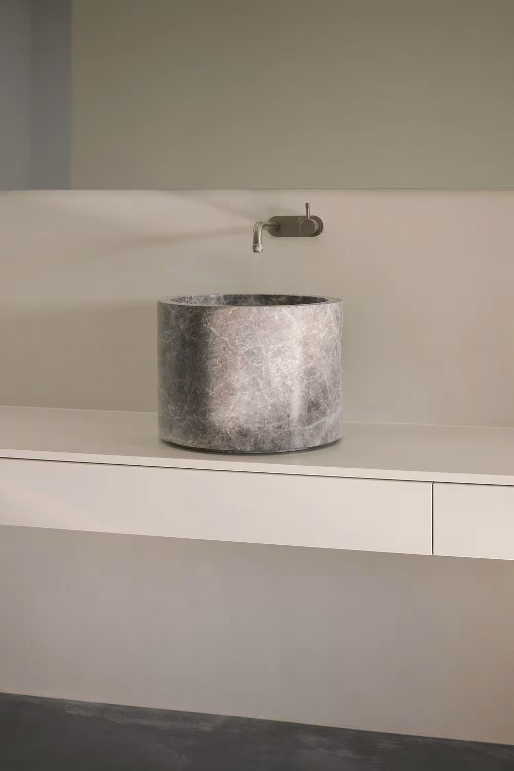 Lavabo de piedra sobre encimera blanca flotante con grifo mural en un baño de la casa de Whispering Smith