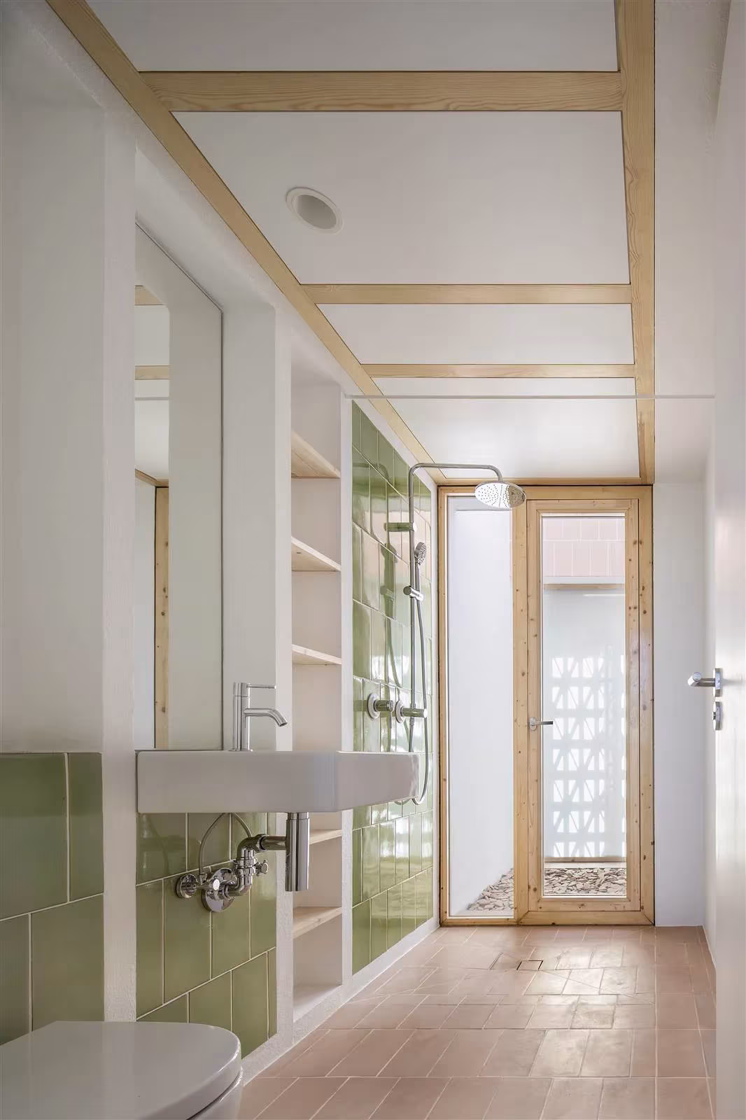 Baño de azulejos verdes y lavabo con marcos de madera de pino que dan a un patio en Es Pou