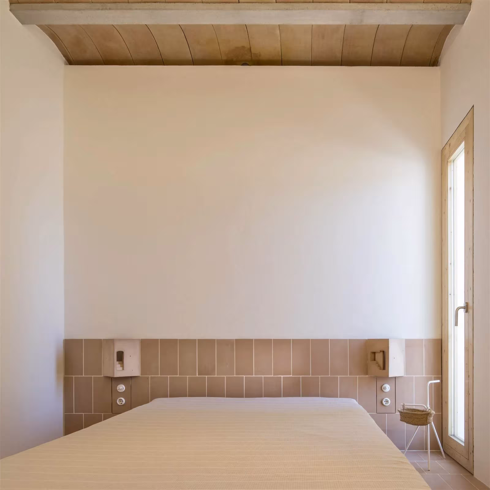 Dormitorio blanco con cabecero de azulejo terracota y techo de madera en Es Pou, Formentera