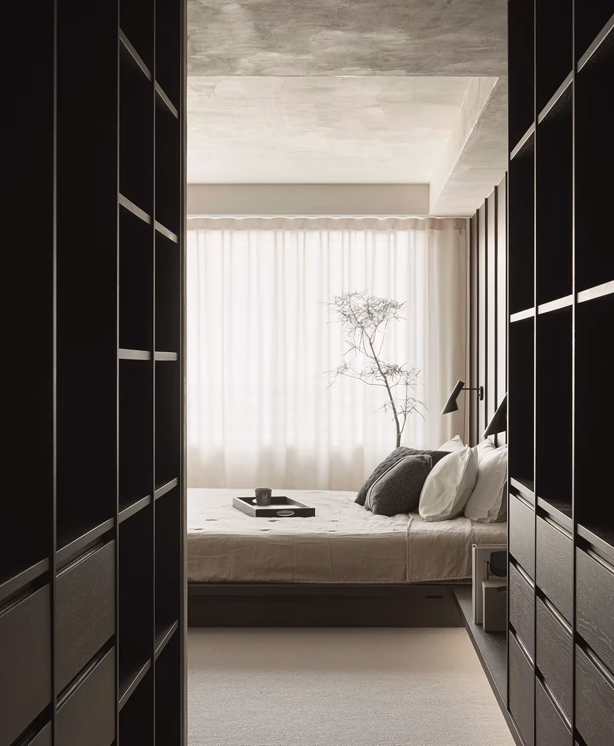 Dormitorio visto entre dos armarios de madera oscura con cortinas de gasa, en la reforma de Norm Architects y Keiji Ashizawa
