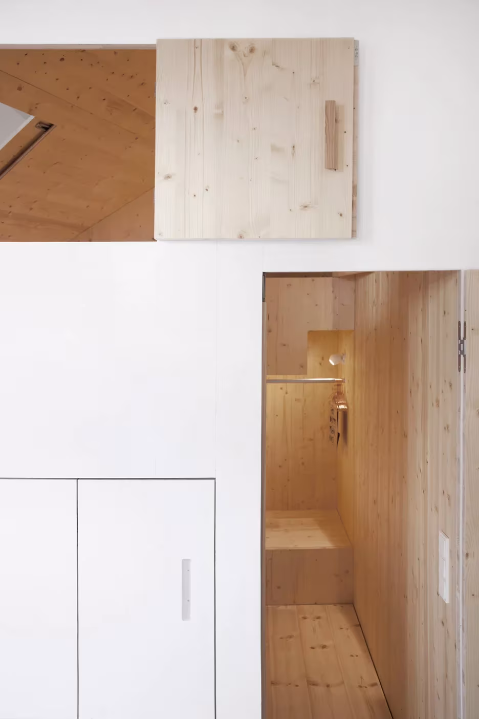 Hueco de abeto con ducha tras un panel pivotante y armarios blancos en la casa de The Garden Room, Berlín