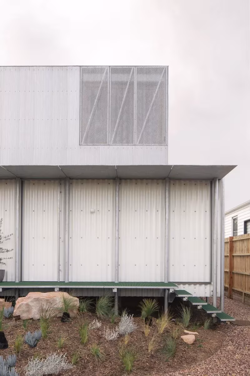 Casa AB de Office Mi Ji sobre pilotes de acero, con volumen superior de celosía metálica y escalera al jardín, Australia