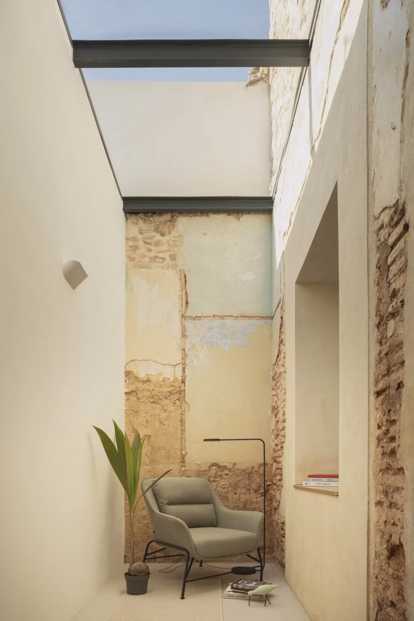 Patio estrecho con lucernario, paramentos desconchados y un sillón en la Casa del Calvari de Endalt, Valencia
