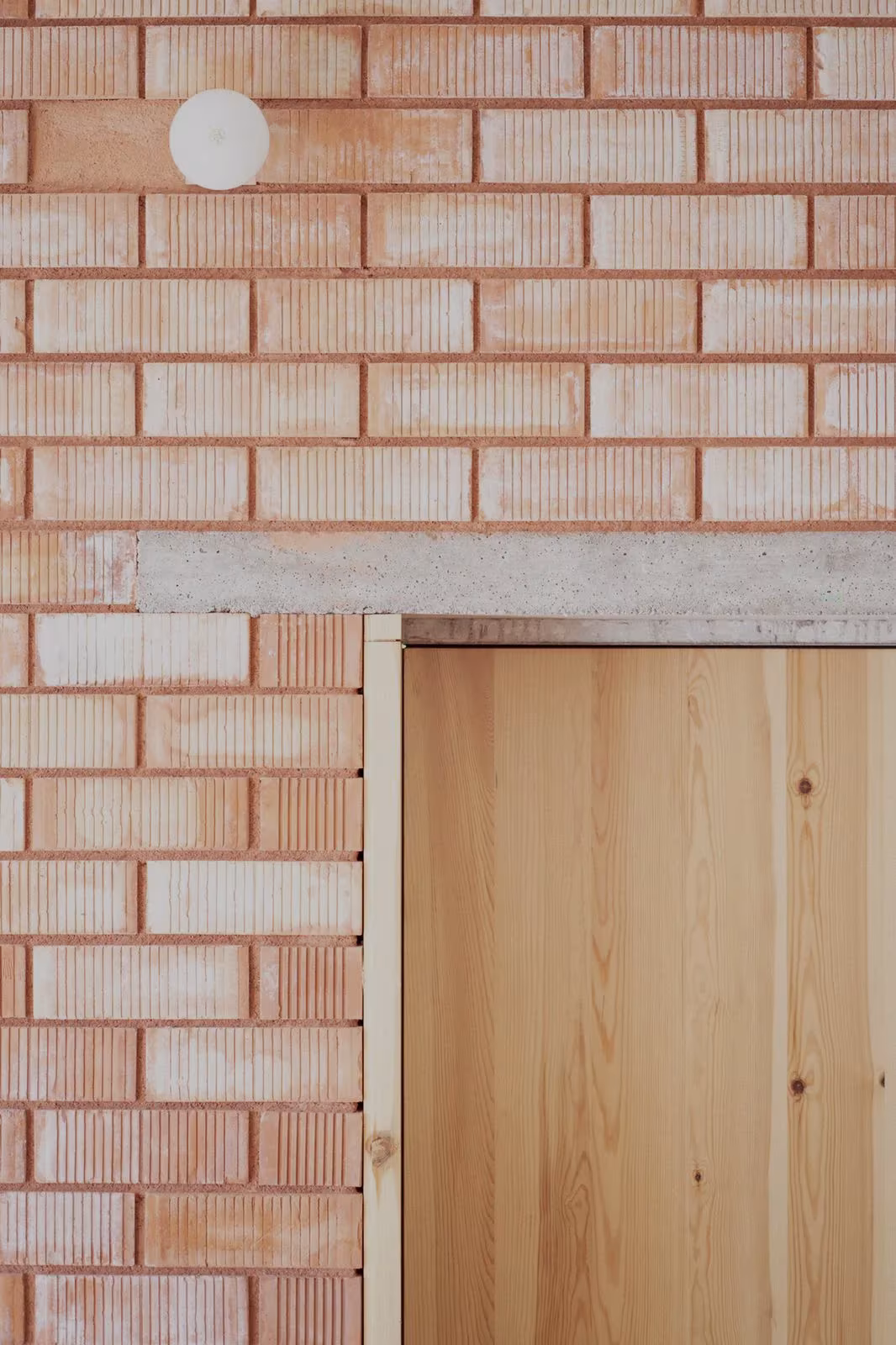 Muro de ladrillo cerámico con dintel de hormigón y puerta de madera de pino en la Casa Dosmurs de MESURA, Alella