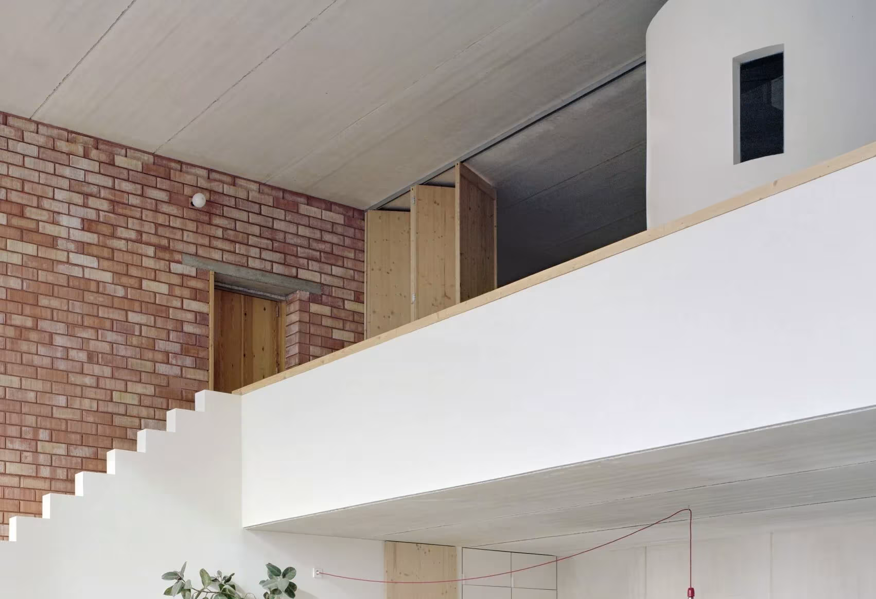 Altillo con cierre modular de madera y muro de ladrillo sobre el salón blanco de la Casa Dosmurs