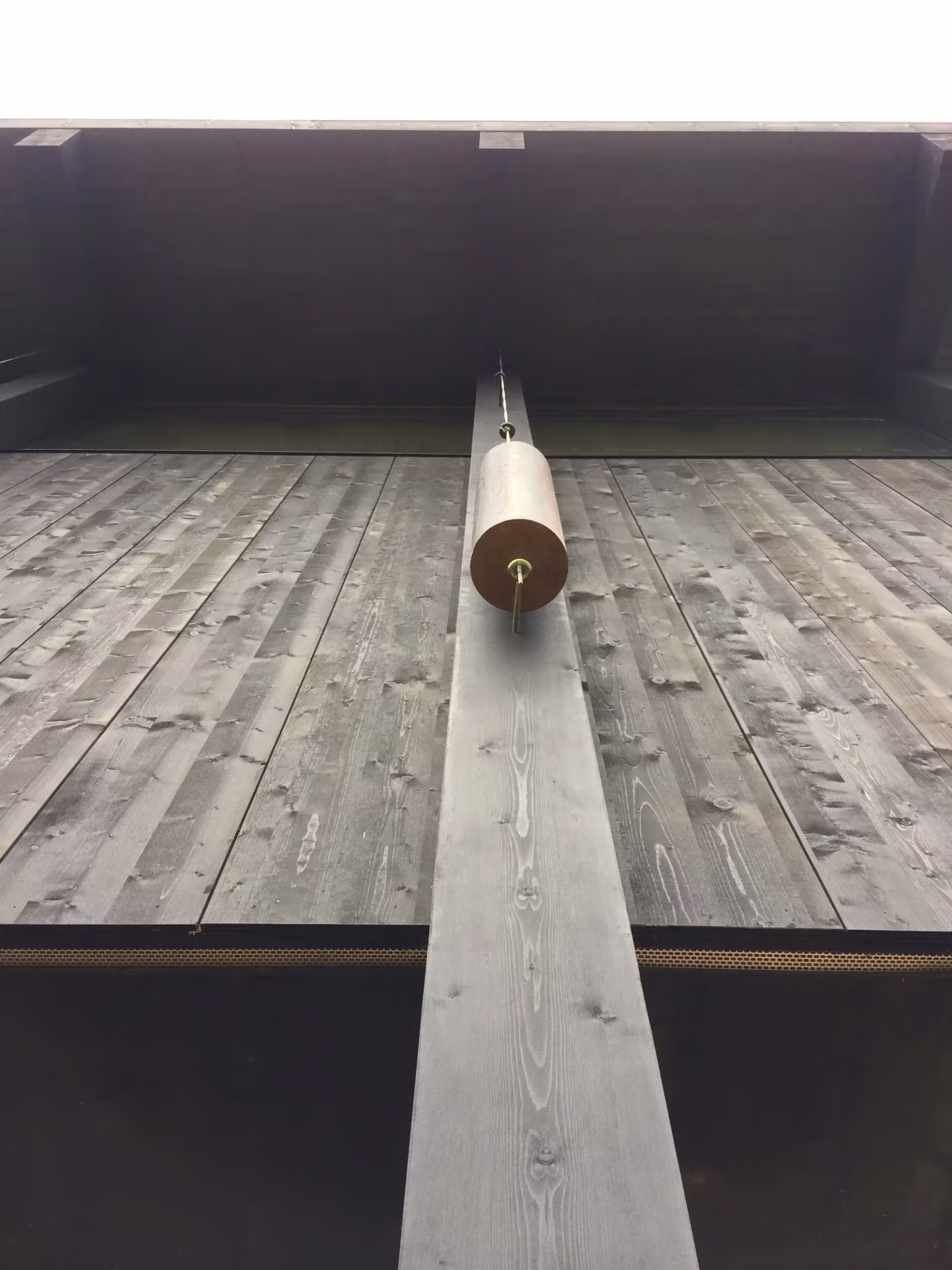 Detalle de un suelo de tablas de madera gris con una viga y una espiga redonda en el proyecto de LVPH en Treyvaux
