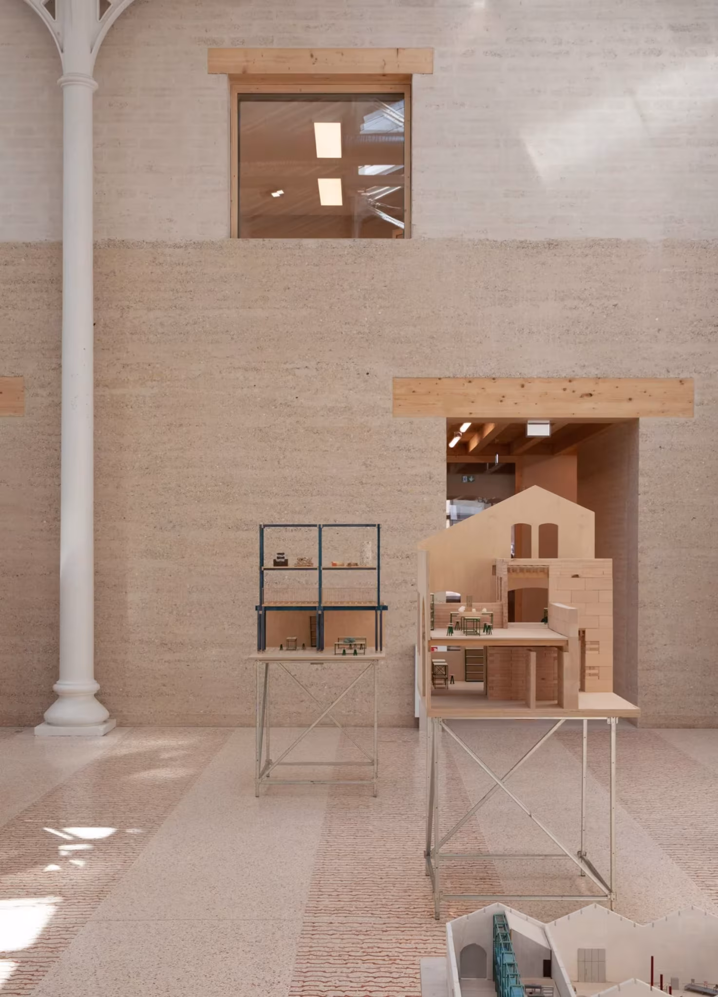 Muro de tierra apisonada con ventana alta, columna de fundición y maquetas en Le Magasin Électrique