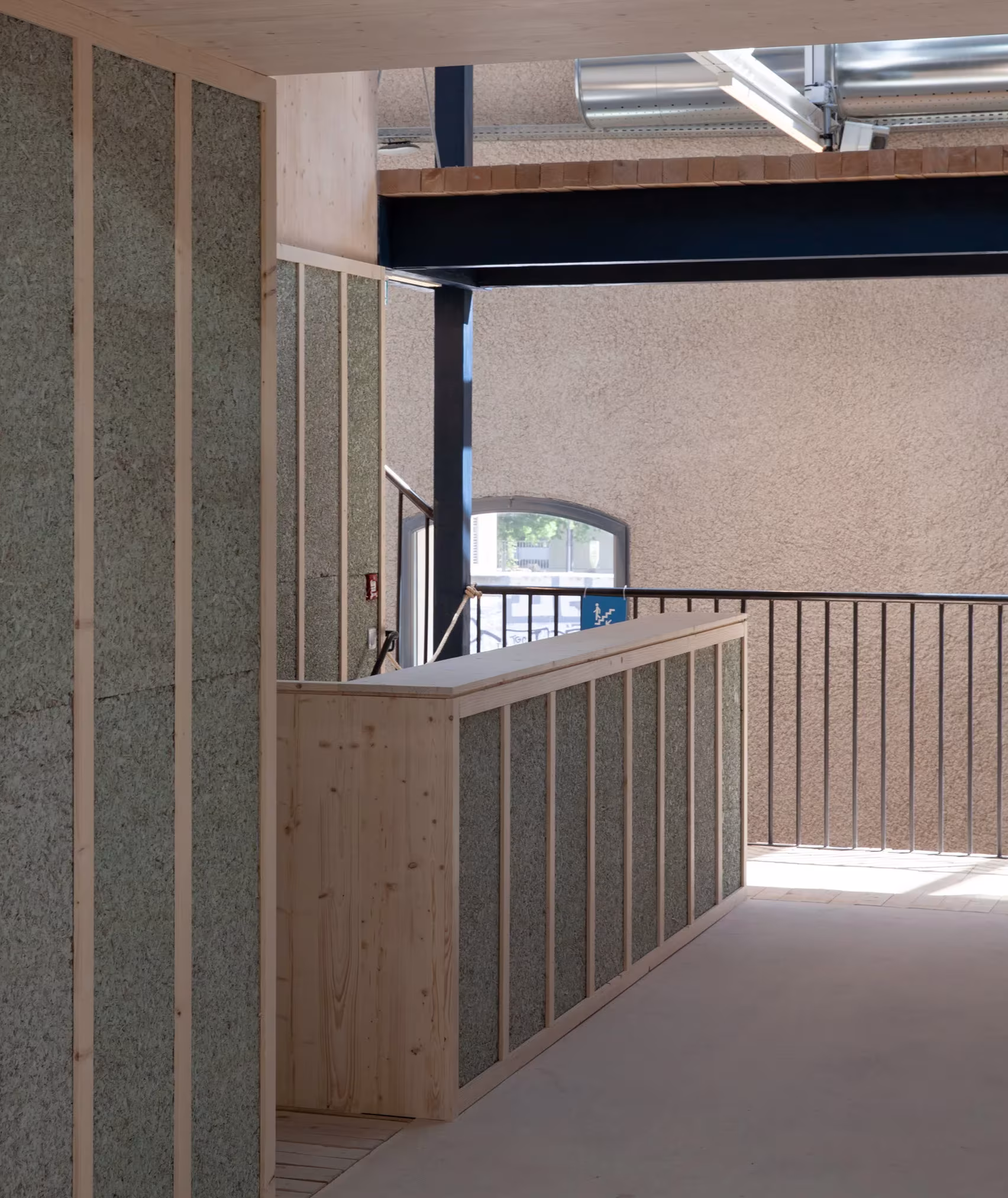 Pared de fibra vegetal con estructura de madera y barandilla metálica en Le Magasin Électrique