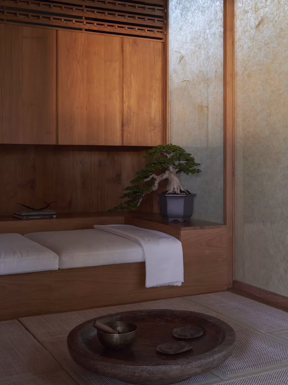 Rincón de descanso con cama baja y bonsái entre armarios de madera en HER