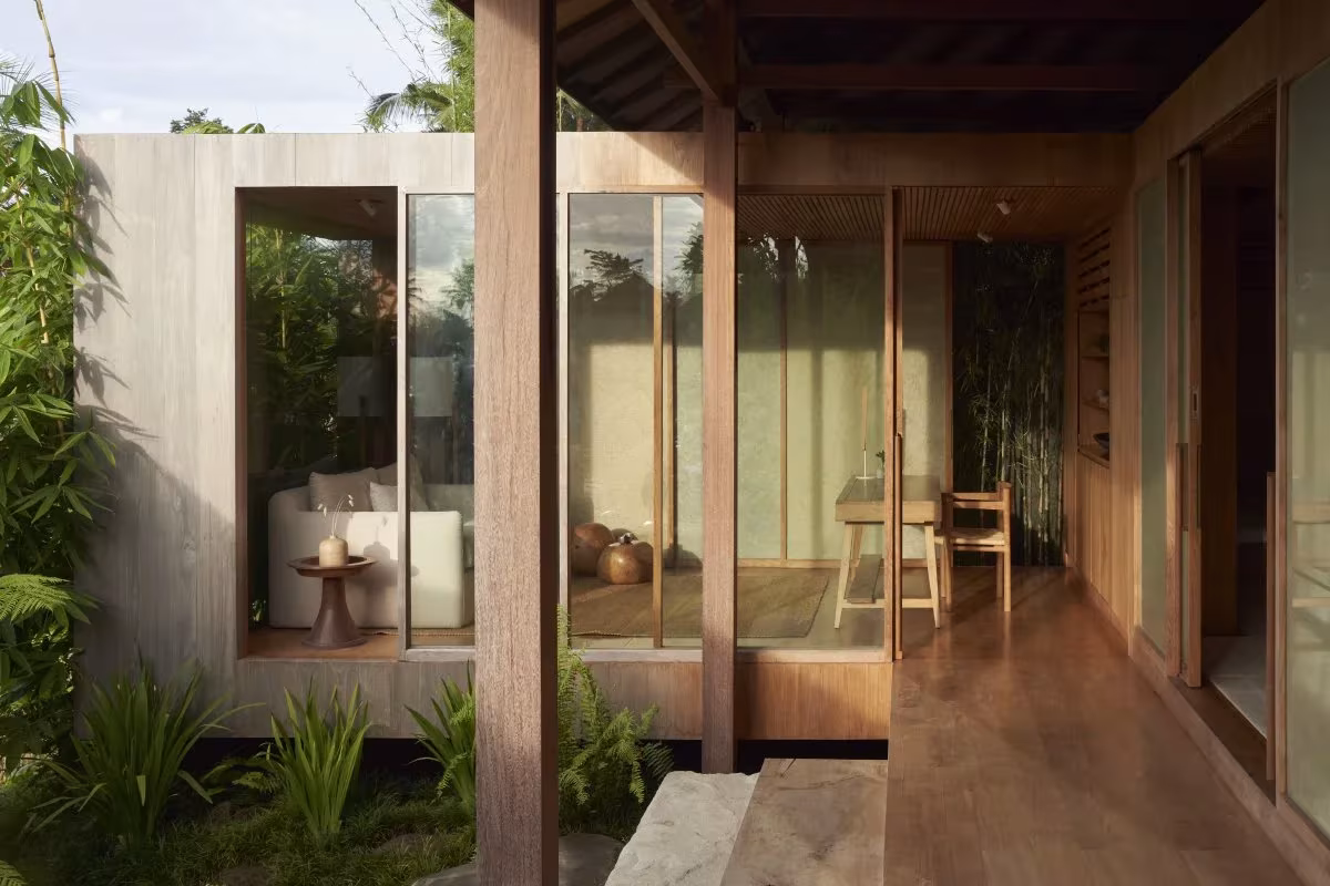 Galería de madera con suelo de tarima y ventanales hacia el jardín tropical de HER