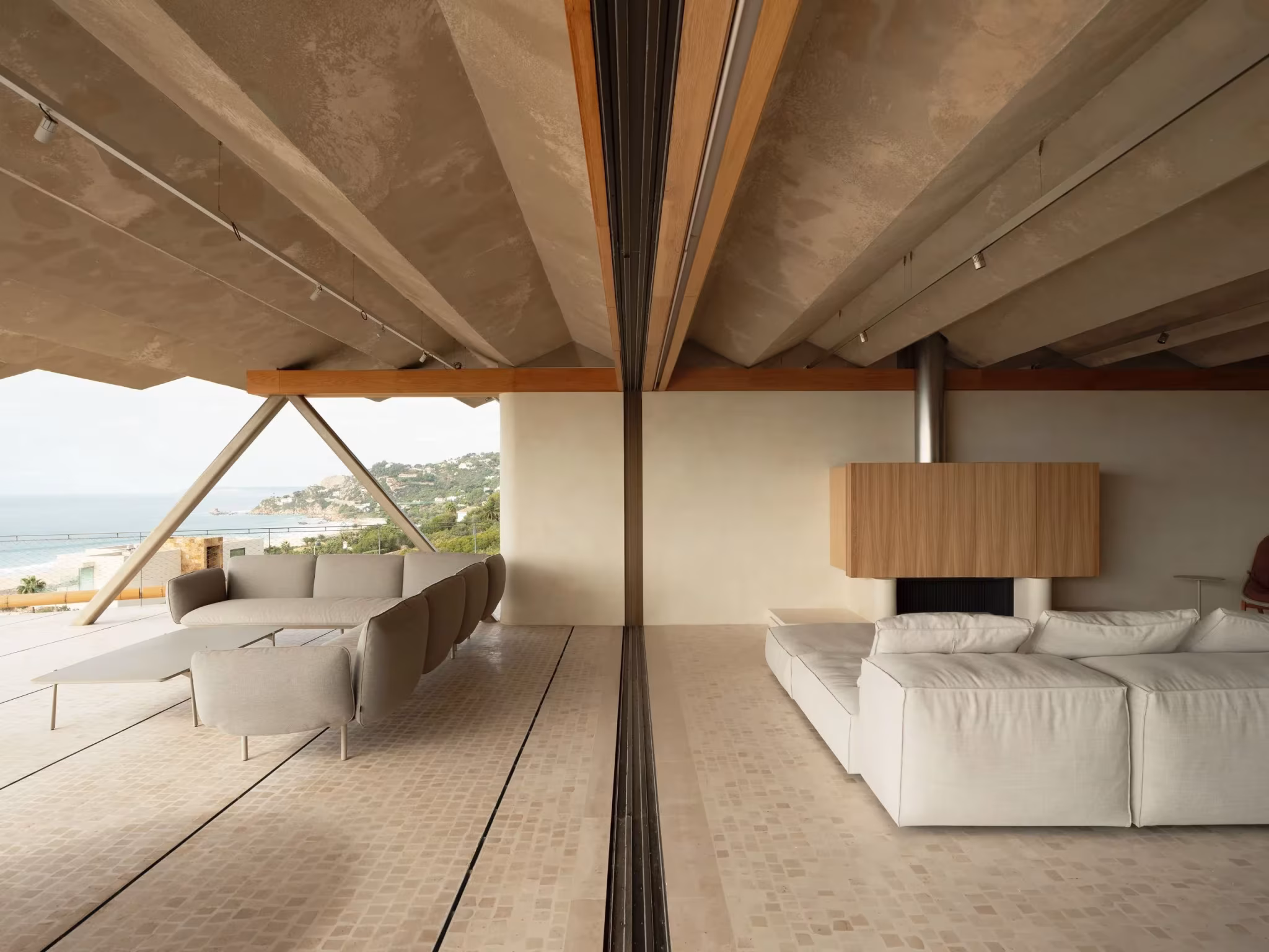 Salón de techo de vigas de madera abierto a la terraza con vistas a la costa, refugio de Langarita Navarro