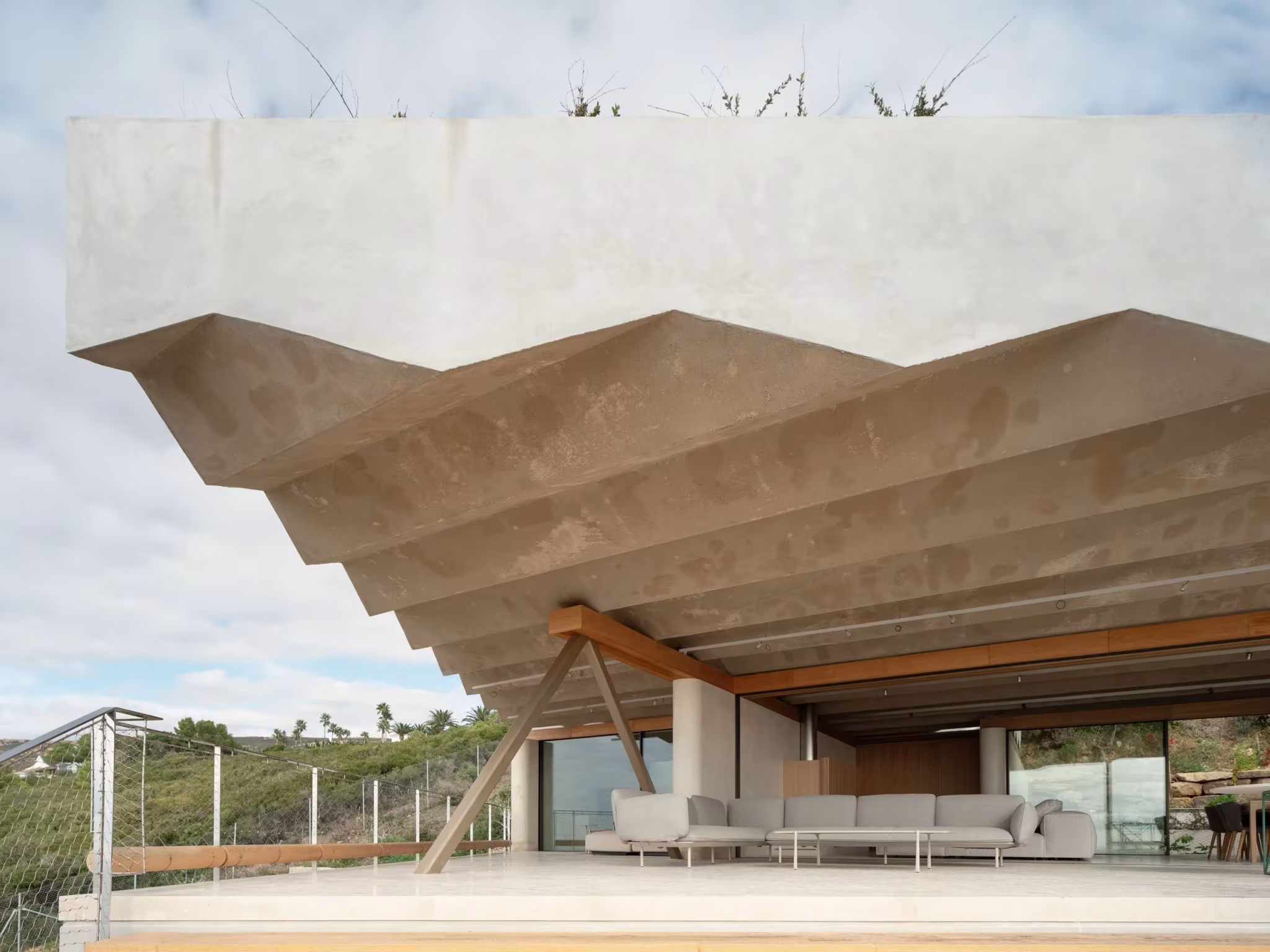 Cubierta de hormigón plegada sobre la terraza con sofás del refugio de Langarita Navarro
