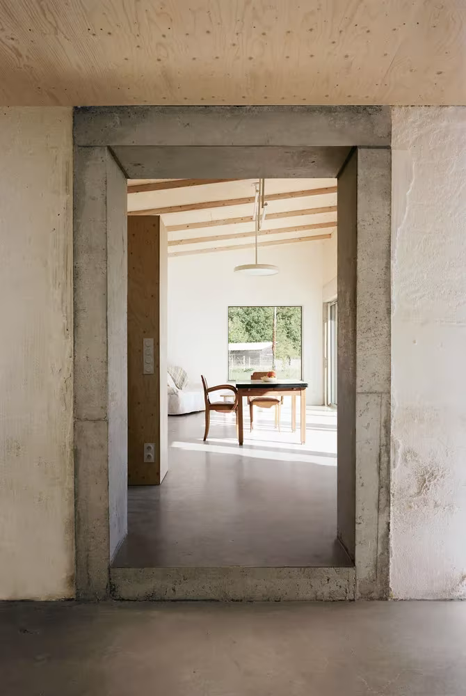 Vista interior de la transformación de un granero en una casa de vacaciones en Francia de Migeon Architecture.  Detalle de jamba y dintel de hormigón