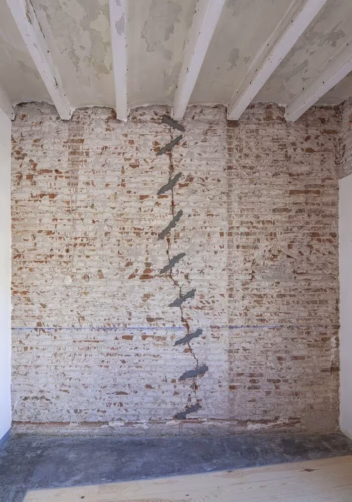 Muro de ladrillo visto con grieta y vigas de madera en el interior de La Carbonería, Barcelona