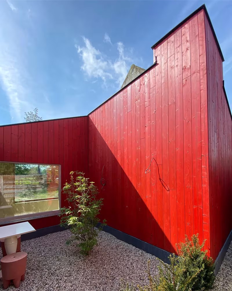 Fotografía exterior parte roja de secuoya del antiguo granero en Gijzenzele rehabilitado por Atelier Tom Vanhee