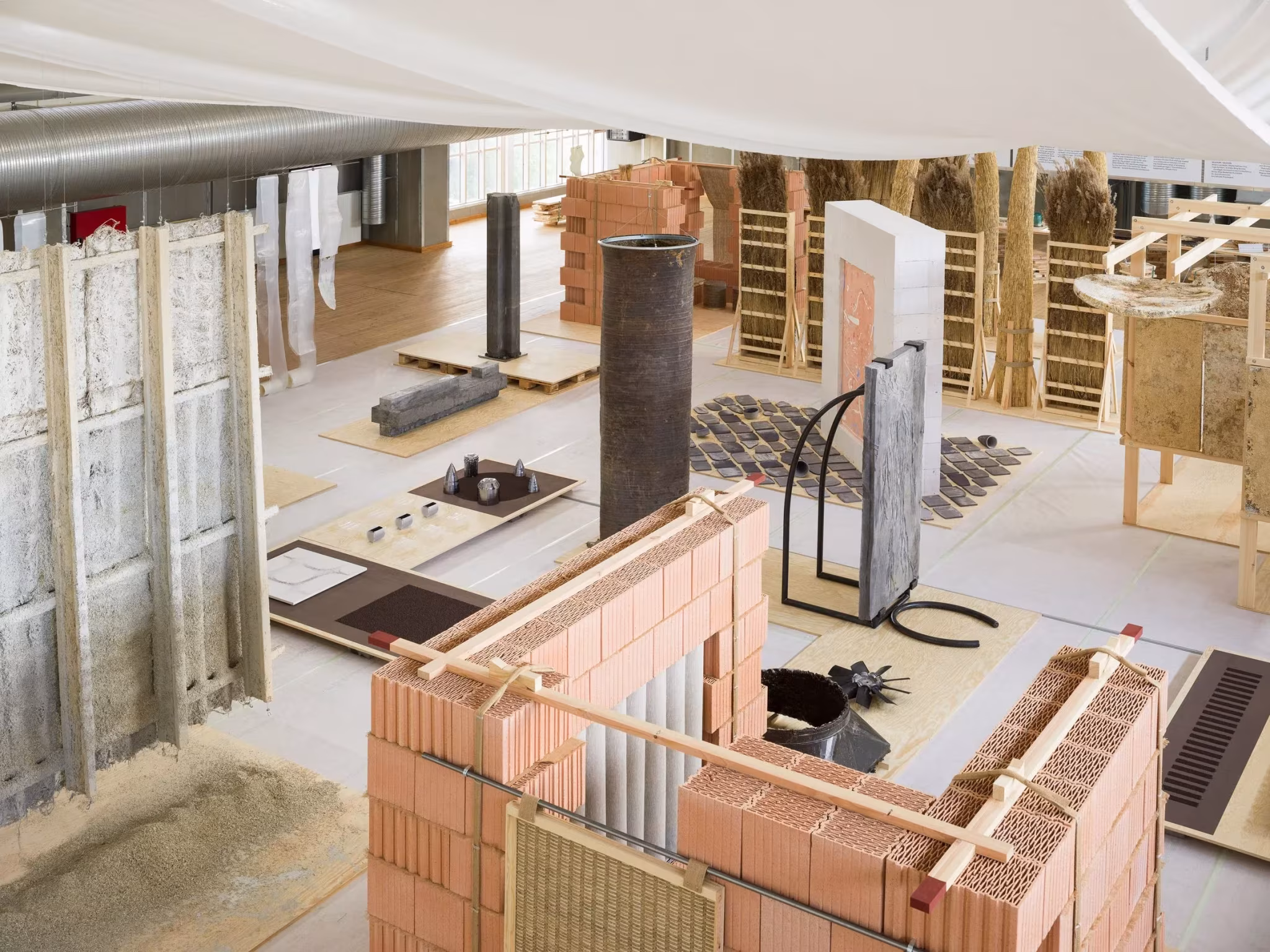 Vista cenital de la exposición Reset Materials con muros de ladrillo cerámico, fibras vegetales y estructuras de madera