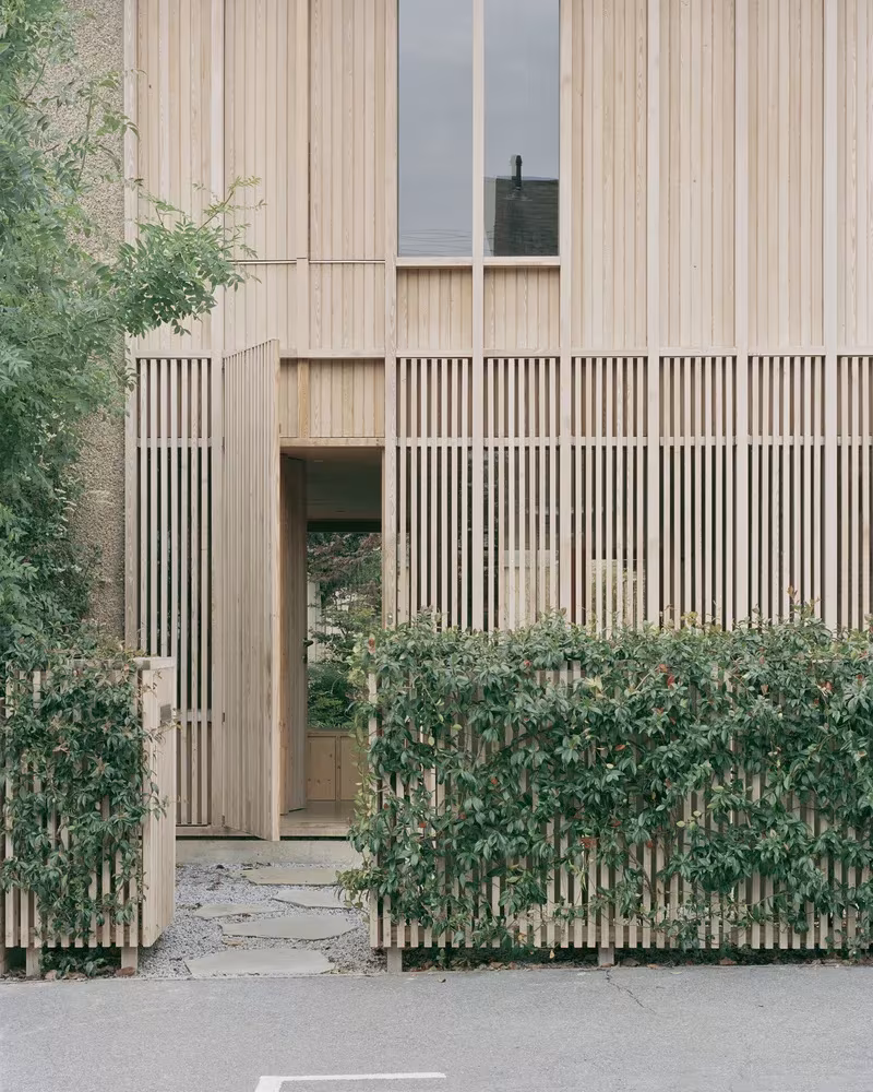 Detalle de la fachada de lamas de madera de la Casa y estudio Spruce con entrada entre setos