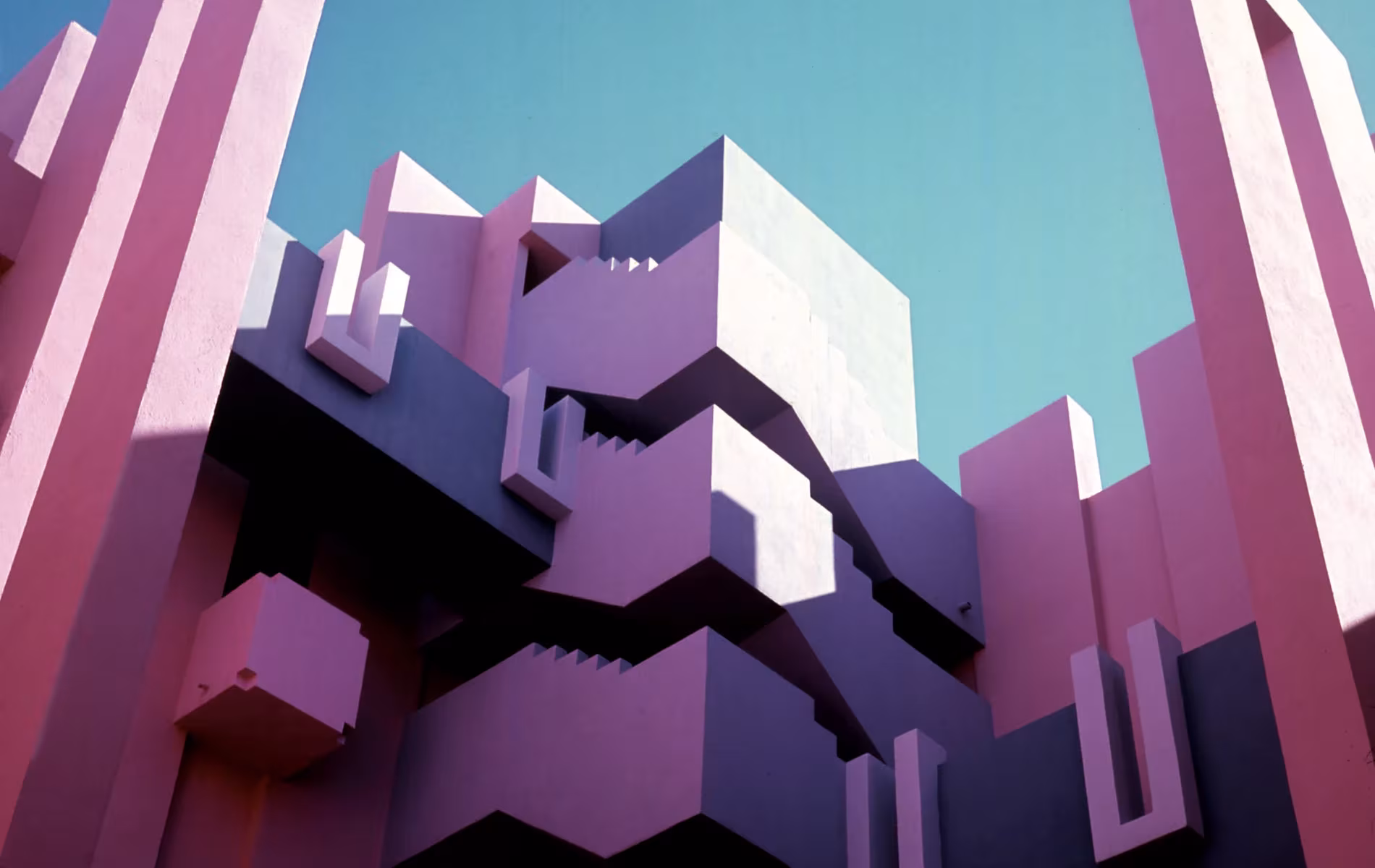 Escaleras y volúmenes rosas y violetas de La Muralla Roja de Ricardo Bofill vistos desde abajo