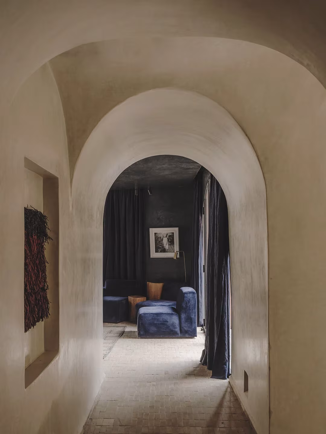 Pasillo abovedado y encalado de Maison Brummell Majorelle que lleva a una sala con sillones azules