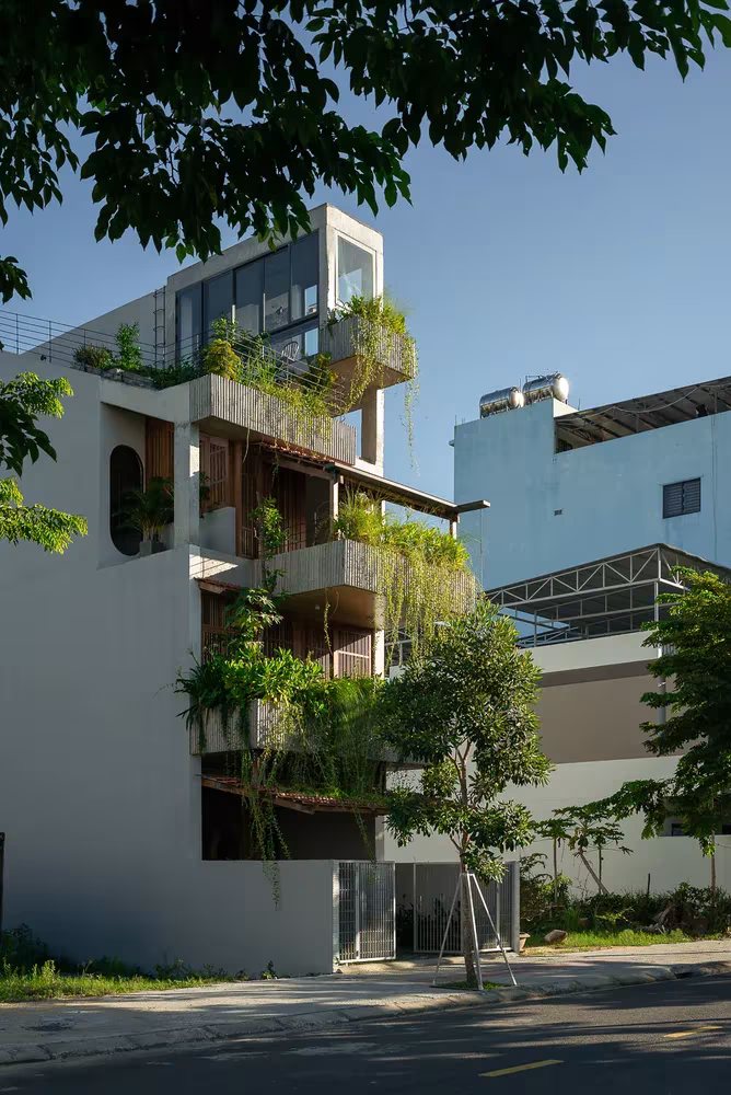 Fachada de la Casa Hien de Winhouse Architecture con terrazas escalonadas y plantas colgantes en una calle