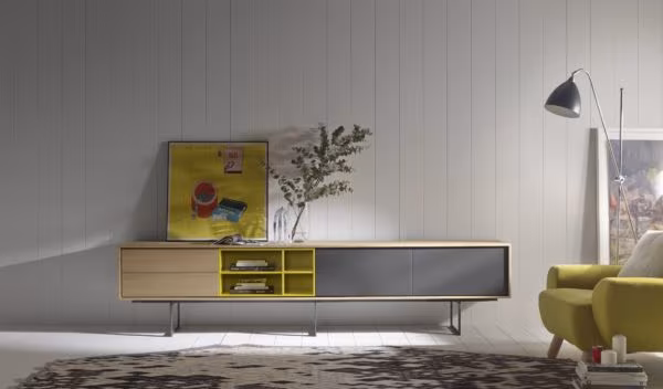 Timber sideboard with yellow compartments and grey doors beneath a floor lamp and a green armchair