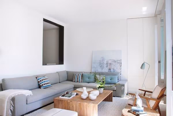 Living room with a grey L-shaped sofa, a timber coffee table and a floor lamp in the Barrio de Salamanca renovation