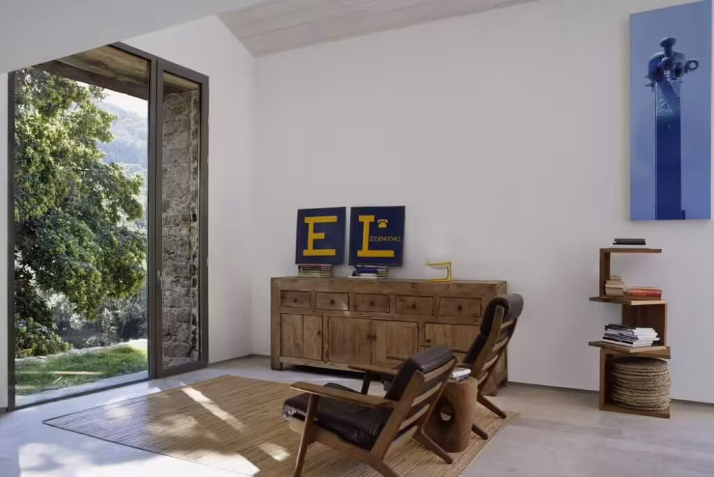 Living room in an Ábaton project with an antique Chinese sideboard, wooden armchairs and a door open to the landscape