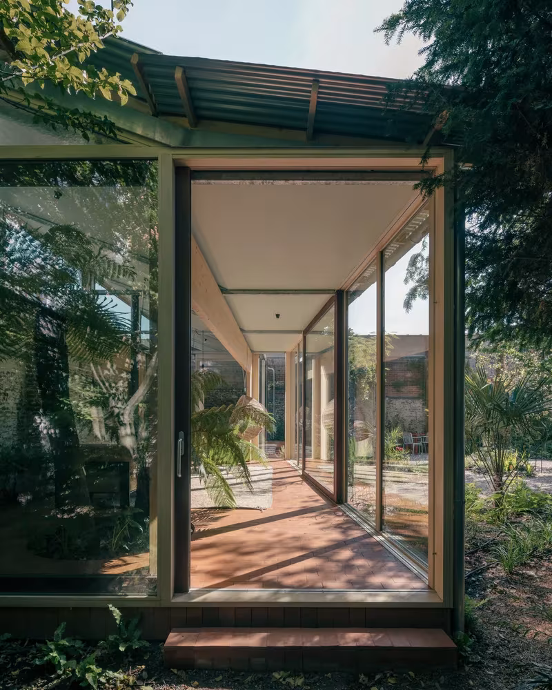 Galería acristalada de Martelaar House con suelo de baldosa roja y cubierta metálica ligera