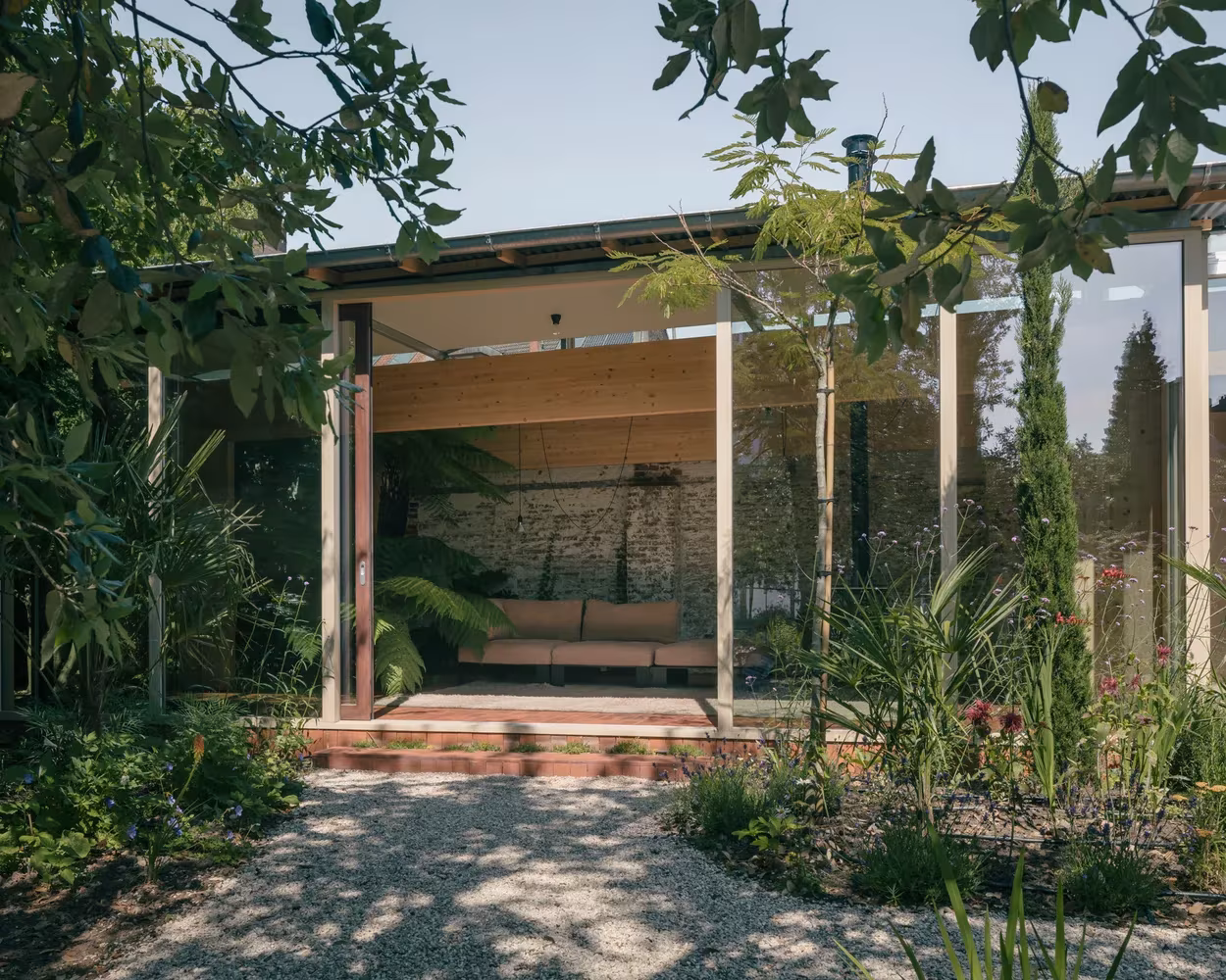 Pabellón de vidrio y madera de Martelaar House visto desde el jardín de gravilla entre la vegetación