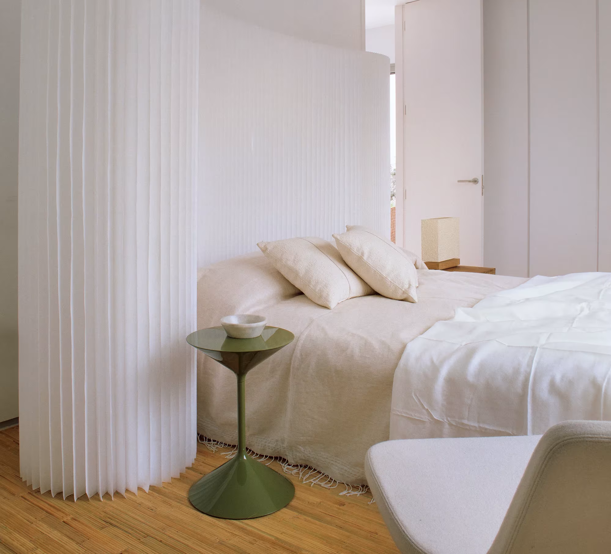 Dormitorio con cama blanca separado por una pared blanca plegada y curva de molo
