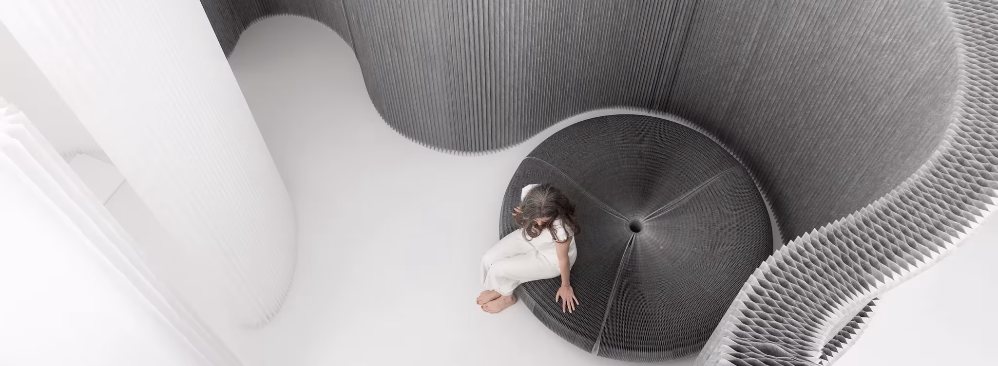Vista cenital de una persona recostada en un asiento en espiral de textil y aluminio de molo