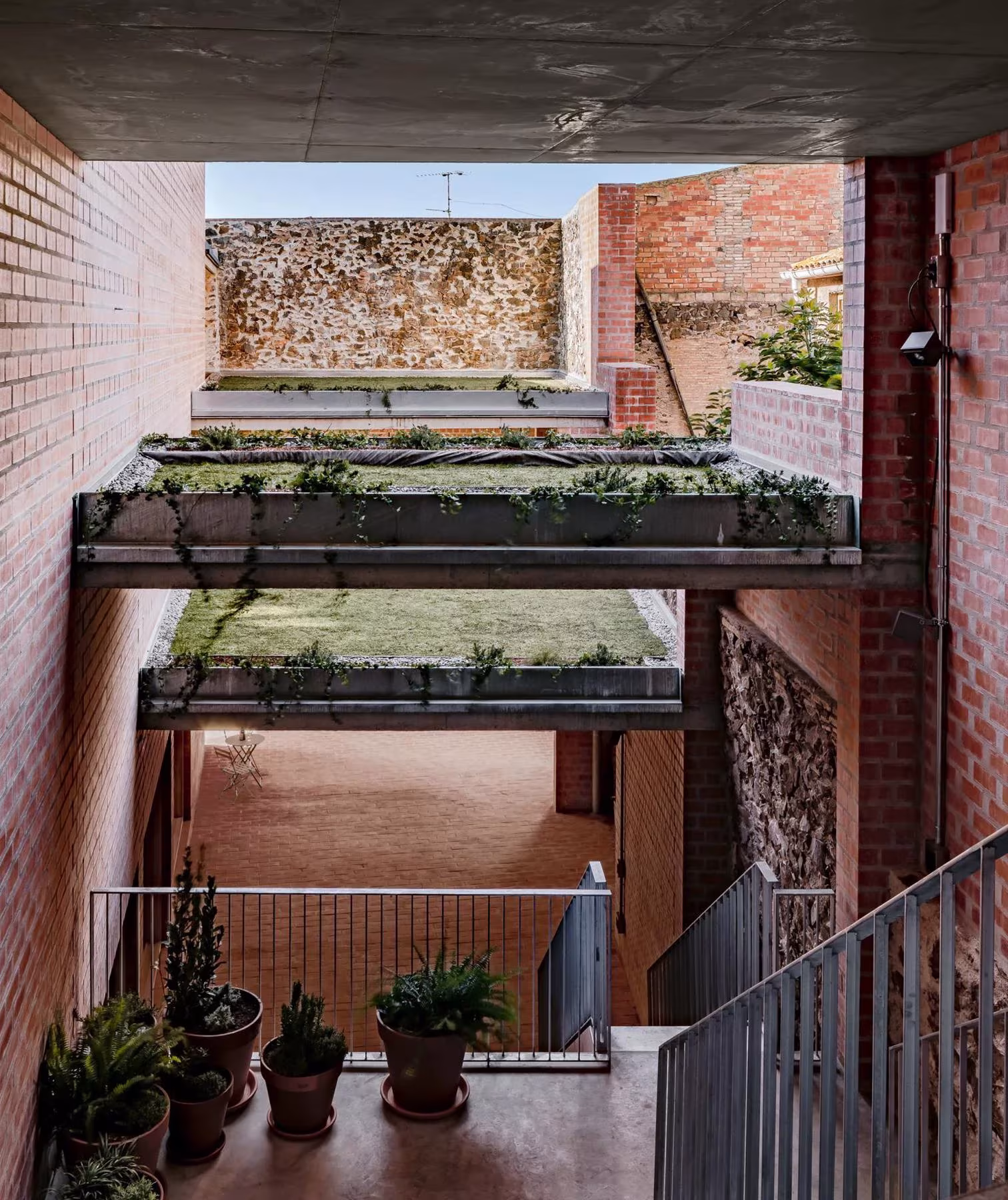 Patio vertical de las Bodegas Clos Pachem con jardineras colgadas, muros de ladrillo y macetas