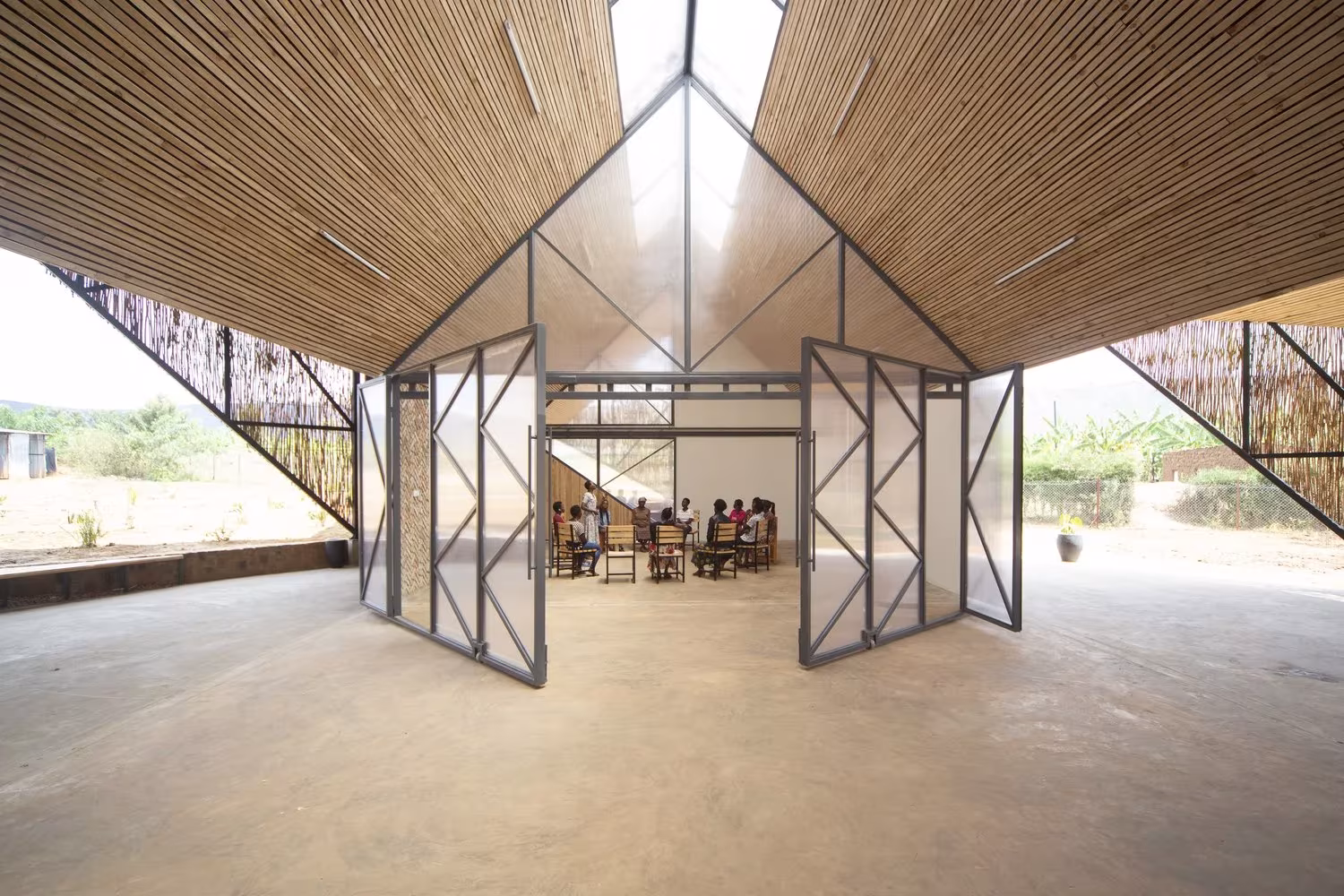 Aula del Centro Komera con puertas acristaladas abiertas bajo un techo de madera a dos aguas