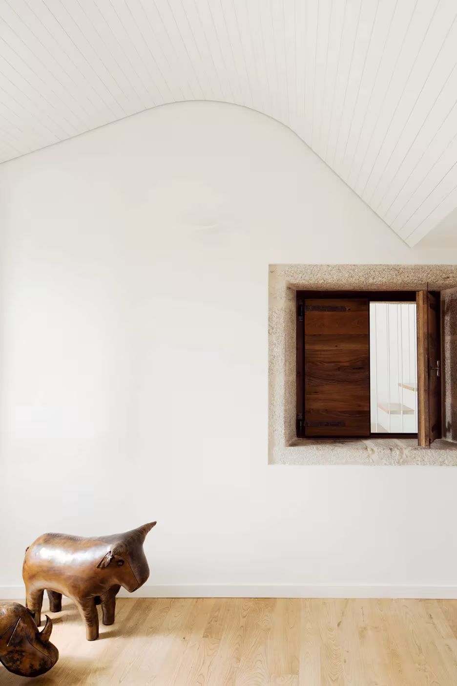 Estancia blanca de la Casa do Medio con techo curvo, ventana de piedra y escultura de toro en el suelo