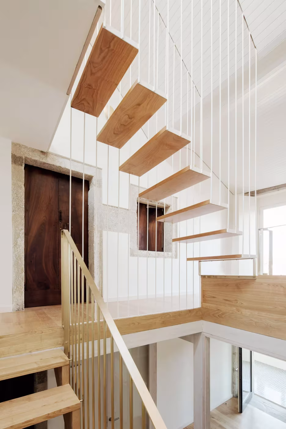 Escalera de peldaños volados de madera colgada de varillas finas en la Casa do Medio