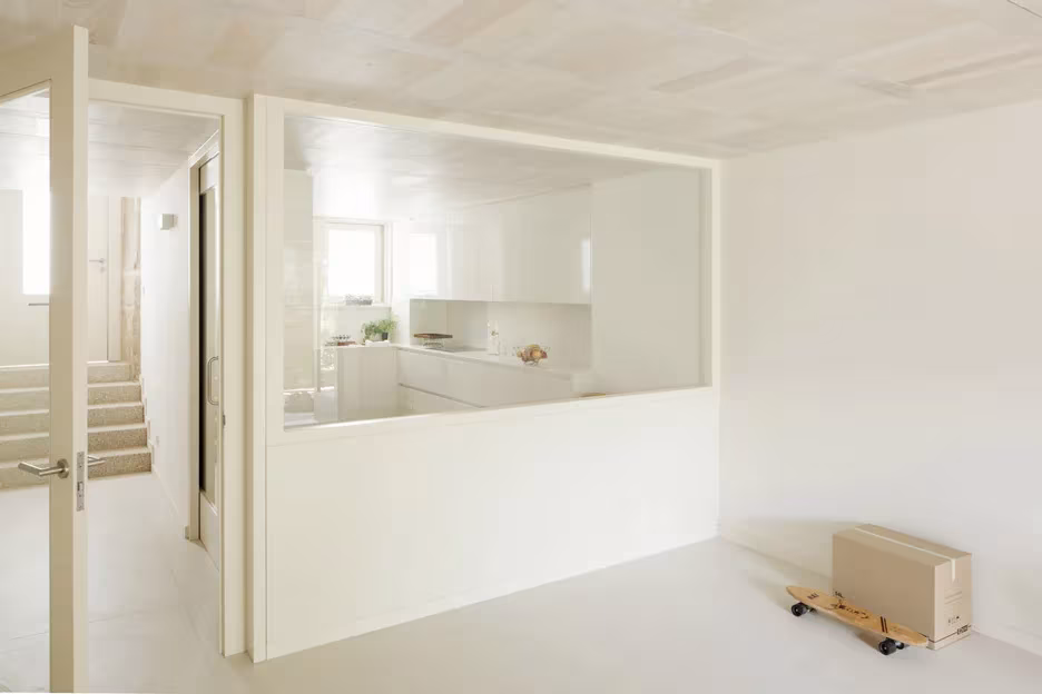 Estancia blanca de la Casa do Medio con ventana interior a la cocina y juguete de madera