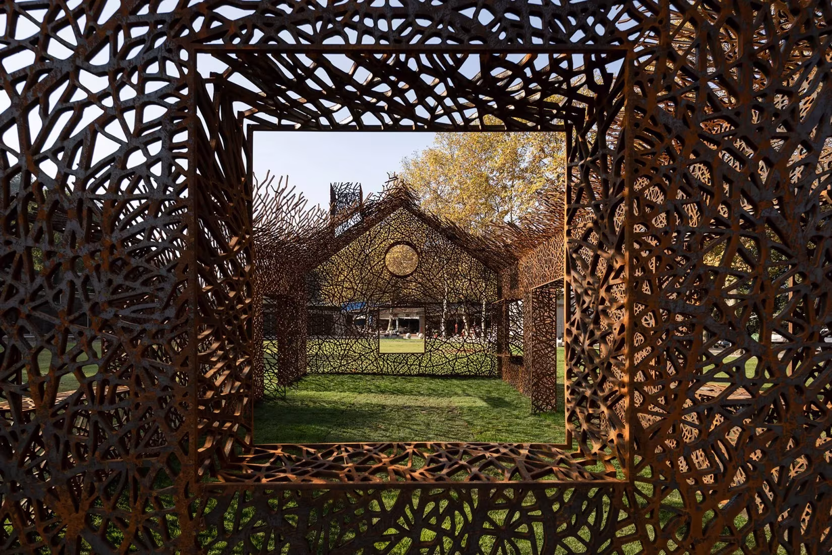 Marco cuadrado en la envolvente de ramas de acero de The Vanished House, que enmarca el jardín y el pabellón