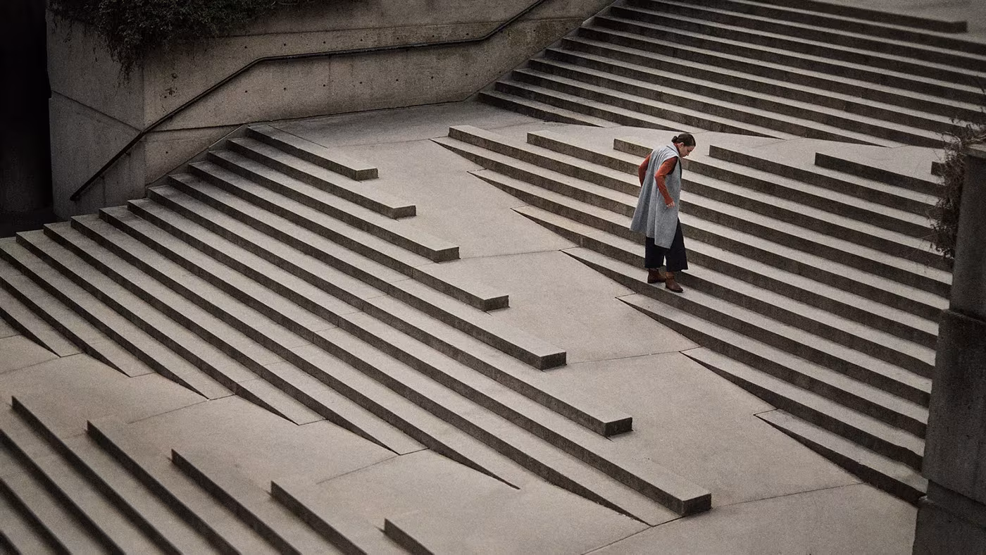 Figura subiendo una escalinata de hormigón con peldaños en diagonal vista desde lo alto