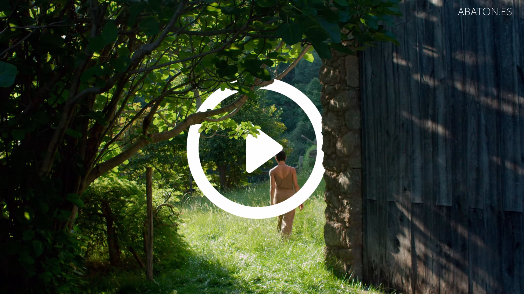 Fotograma de vídeo de Derek Pedros con una figura desnuda en un bosque junto a un muro de madera